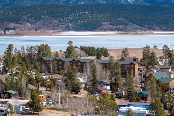 A resort with multiple buildings, a beach, and a mountainous backdrop.