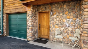 A stone wall exterior with a wooden door and green garage door.
