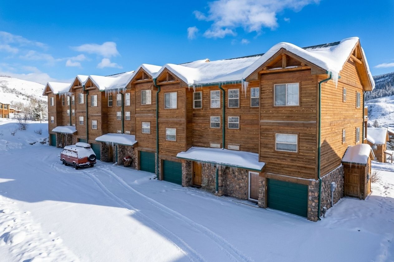 Un bâtiment en bois à plusieurs étages, dont le toit est recouvert de neige, et devant lequel est garé un véhicule.