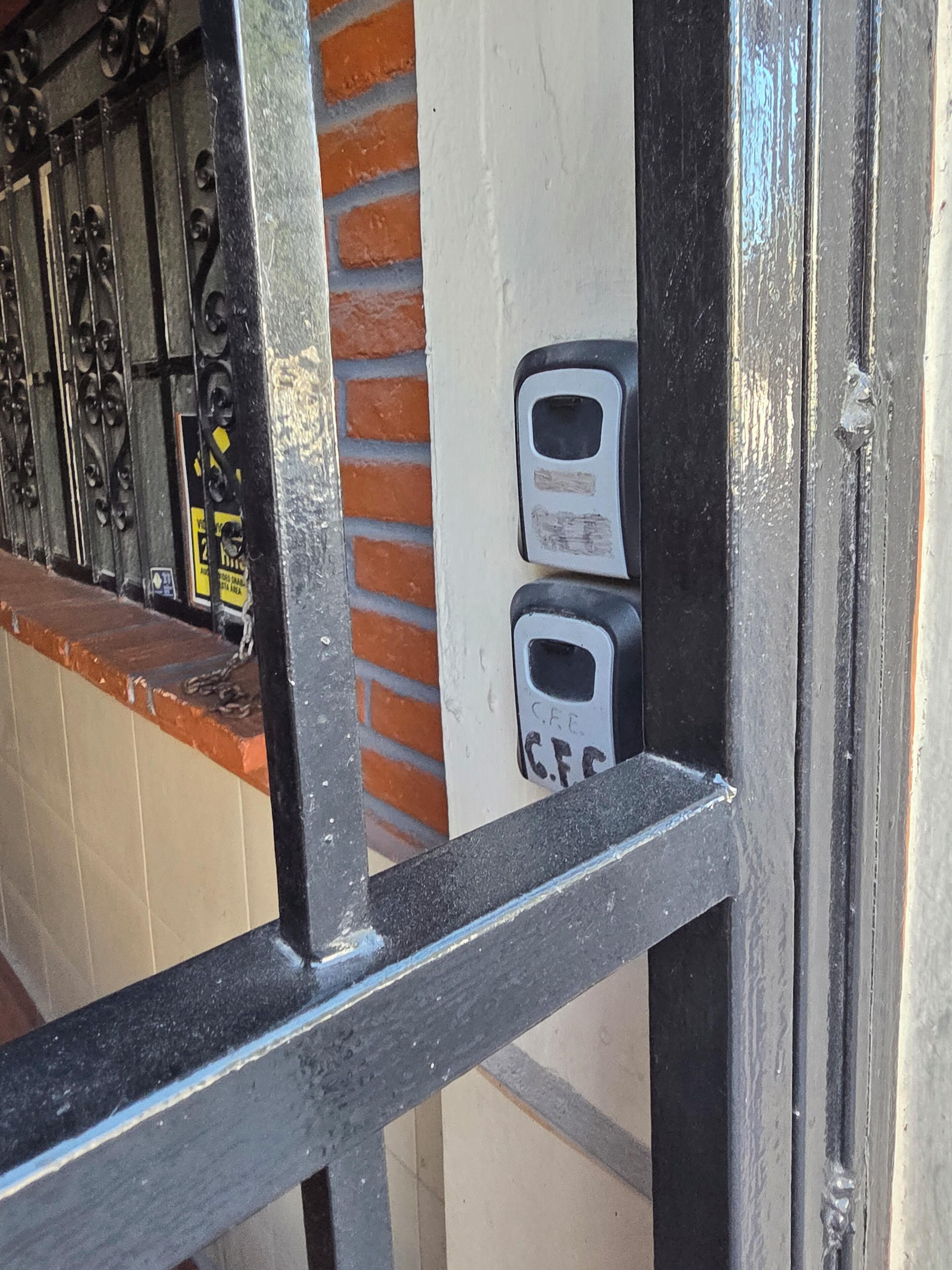 A metal gate with a brick wall and a tiled floor.