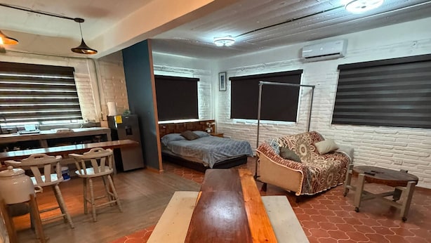 A room with a long wooden table, a sofa, a bed, and a dining area with chairs. - Modern and Cozy Rustic Loft (Puerto Vallarta)