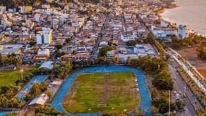 An aerial view of a coastal city with a large stadium, residential buildings, and a mountain in the background. - Modern and Cozy Rustic Loft (Puerto Vallarta)