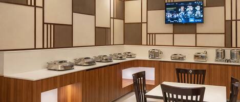 Una cocina moderna con encimera de madera, electrodomésticos integrados y un televisor de pantalla plana en la pared.