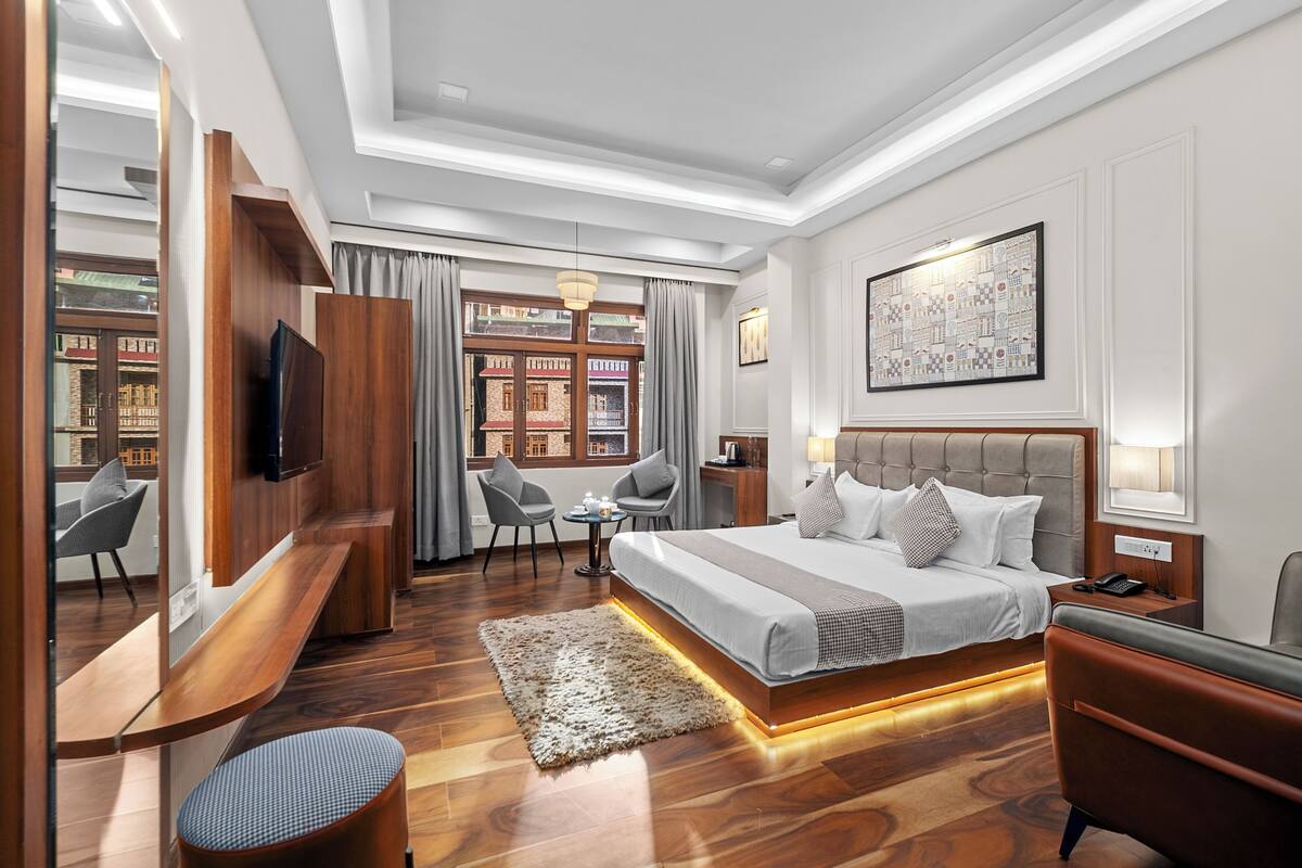 Een moderne hotelkamer met een groot bed, een bureau, een stoel, een televisie en uitzicht op gebouwen.