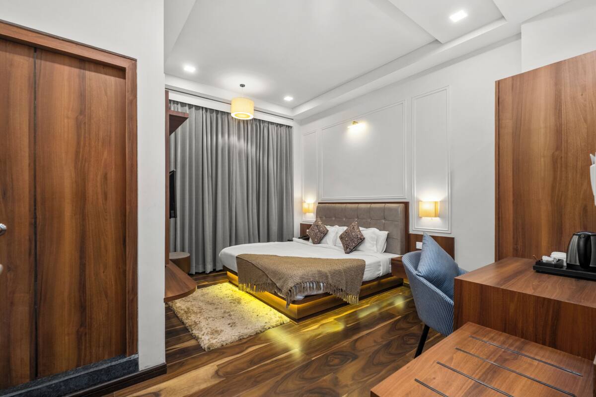 Een moderne hotelkamer met een houten vloer, een bed met hoofdeinde, een bureau en een stoel.