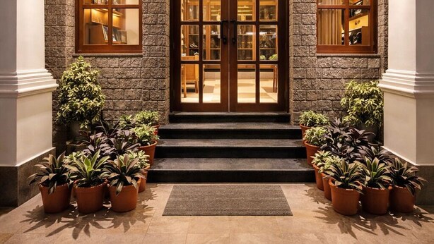 A hotel entrance with a stone facade, double doors, and potted plants.