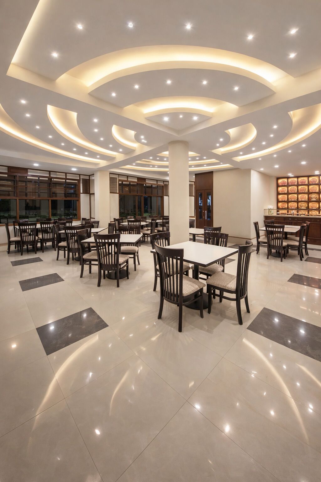 Un vaste espace dédié à la salle à manger, avec de nombreuses tables et chaises, un éclairage encastré au plafond et un plancher poli.