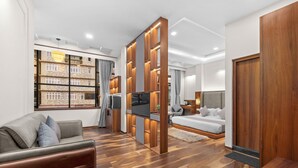 A modern living room with a sofa, TV, wooden partition, and a bedroom with a bed and curtains.