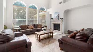 A spacious living room with a fireplace, leather sofas, and large windows. - Relaxed Family Home in Denton / Entire Home (Denton)