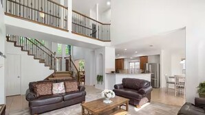 A spacious living area with a staircase, a sofa, a coffee table, and a kitchen in the background. - Relaxed Family Home in Denton / Entire Home (Denton)