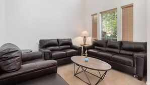 A modern living room with two black leather sofas, a round coffee table, and a lamp. - Relaxed Family Home in Denton / Entire Home (Denton)