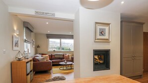 A modern living room with a sofa, a fireplace, and a dining area with a table. - Ambwray (Ambleside)