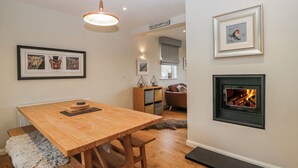 A modern living room with a wooden dining table, a fireplace, and framed artwork on the walls. - Ambwray (Ambleside)