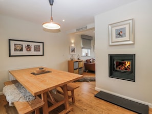 Uma sala de estar moderna com uma mesa de jantar de madeira, lareira e quadros nas paredes.