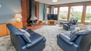 Una sala de estar con chimenea, televisor y dos sofás de cuero.