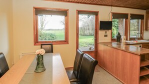 Una cocina con armarios de madera, televisor empotrado y comedor con mesa y sillas.