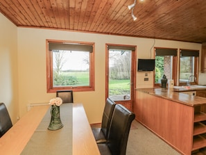 A kitchen with wooden cabinets, a built-in TV, and a dining area with a table and chairs. - Cherry Trees (Grimsby)