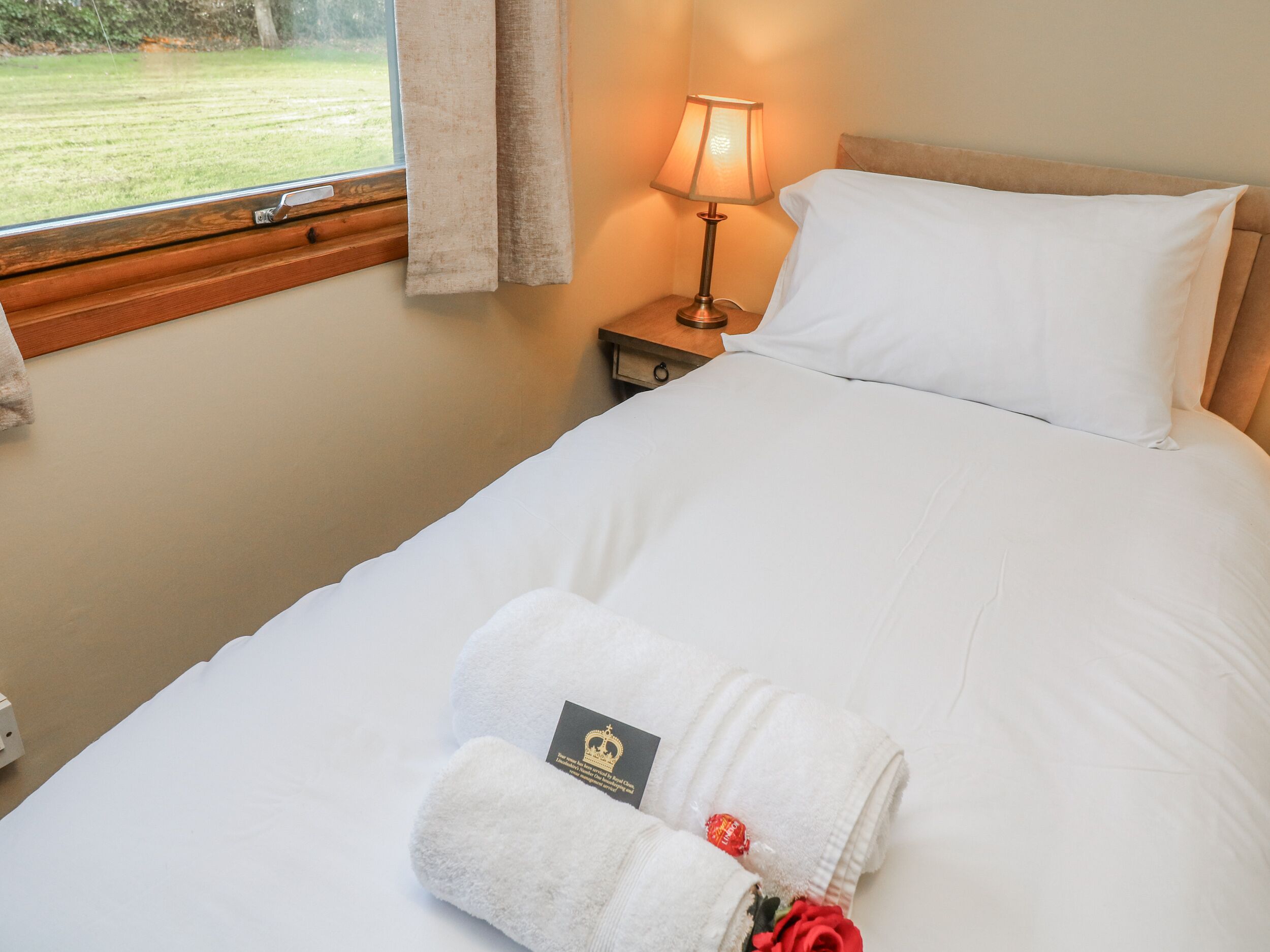 A hotel room with a bed, a nightstand with a lamp, and a window with curtains.