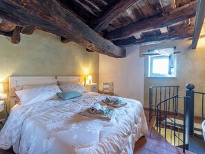Une chambre à coucher avec un lit, des lampes de chevet, une fenêtre et un escalier.