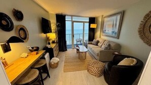 A modern living room with a sofa, coffee table, and dining area. - Our beautiful, one bedroom beachfront condo (sleeps 6) has spectacular views of the Atlantic Ocean from the 17th floor! Newly updated in December 2025 (Myrtle Beach)