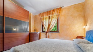 Une chambre à coucher avec un lit, une armoire, une fenêtre avec des rideaux et une table de chevet.