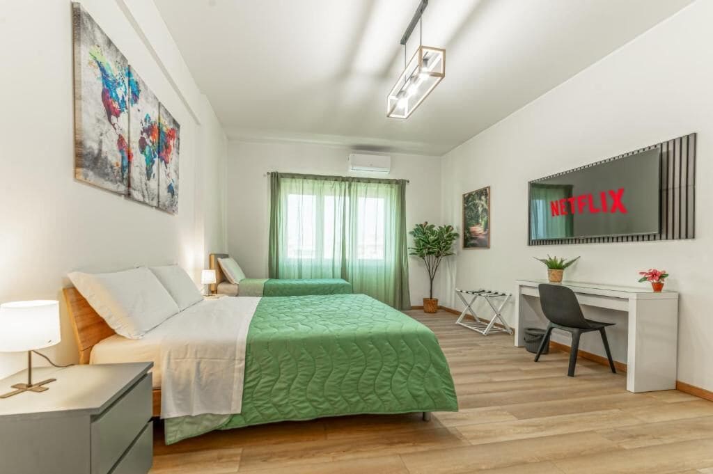 Un dormitorio con cama, escritorio, silla y televisor con el logotipo de Netflix.