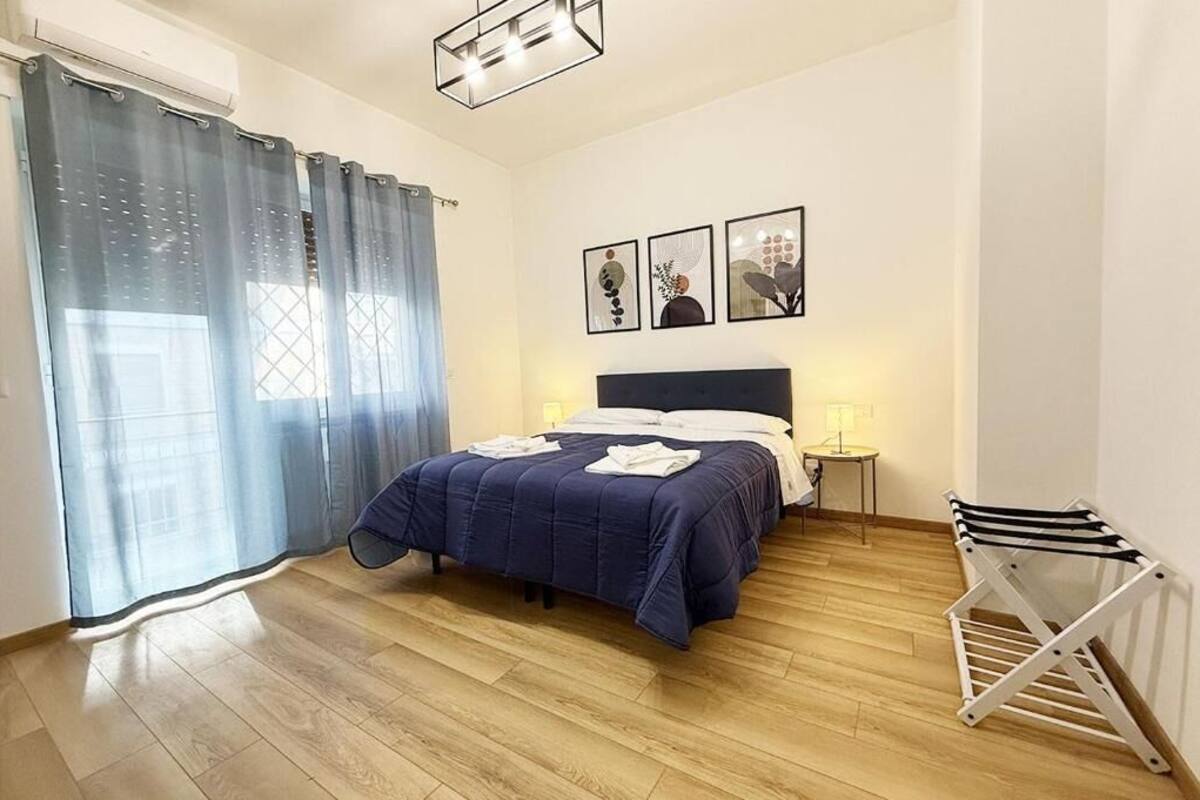 Ein Schlafzimmer mit Bett, Nachttisch mit Lampe, Wand-Fernseher und Wäscheständer.