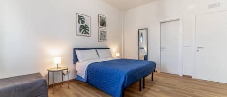 A bedroom with a bed, bedside tables, a bench, a mirror, and a door.