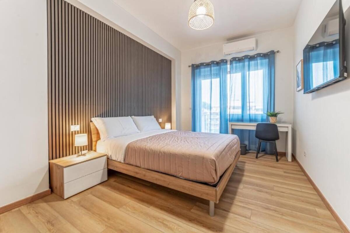 Ein Schlafzimmer mit Bett, Nachttisch, Lampe und Schreibtisch mit Stuhl.