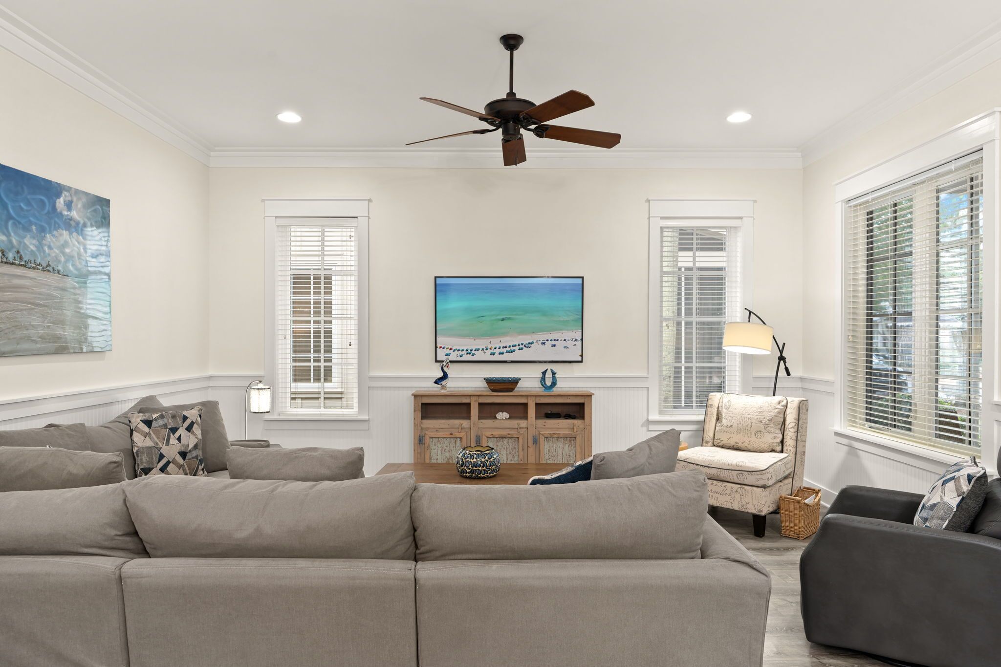 Ein Wohnzimmer mit Deckenventilator, Fernseher, Sofa und Sessel.