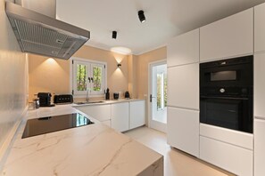 A modern kitchen with a built-in stove, a microwave, and a coffee maker. - Holiday Home in Portopetro with Private Pool, Wi-Fi, and Air Conditioning (Portopetro)