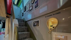 A staircase with a 'NO STANDING ON STAIRS' sign, framed pictures, a mirror, and a small display case with a zebra statue. - No 1 The Depot (Gateshead)