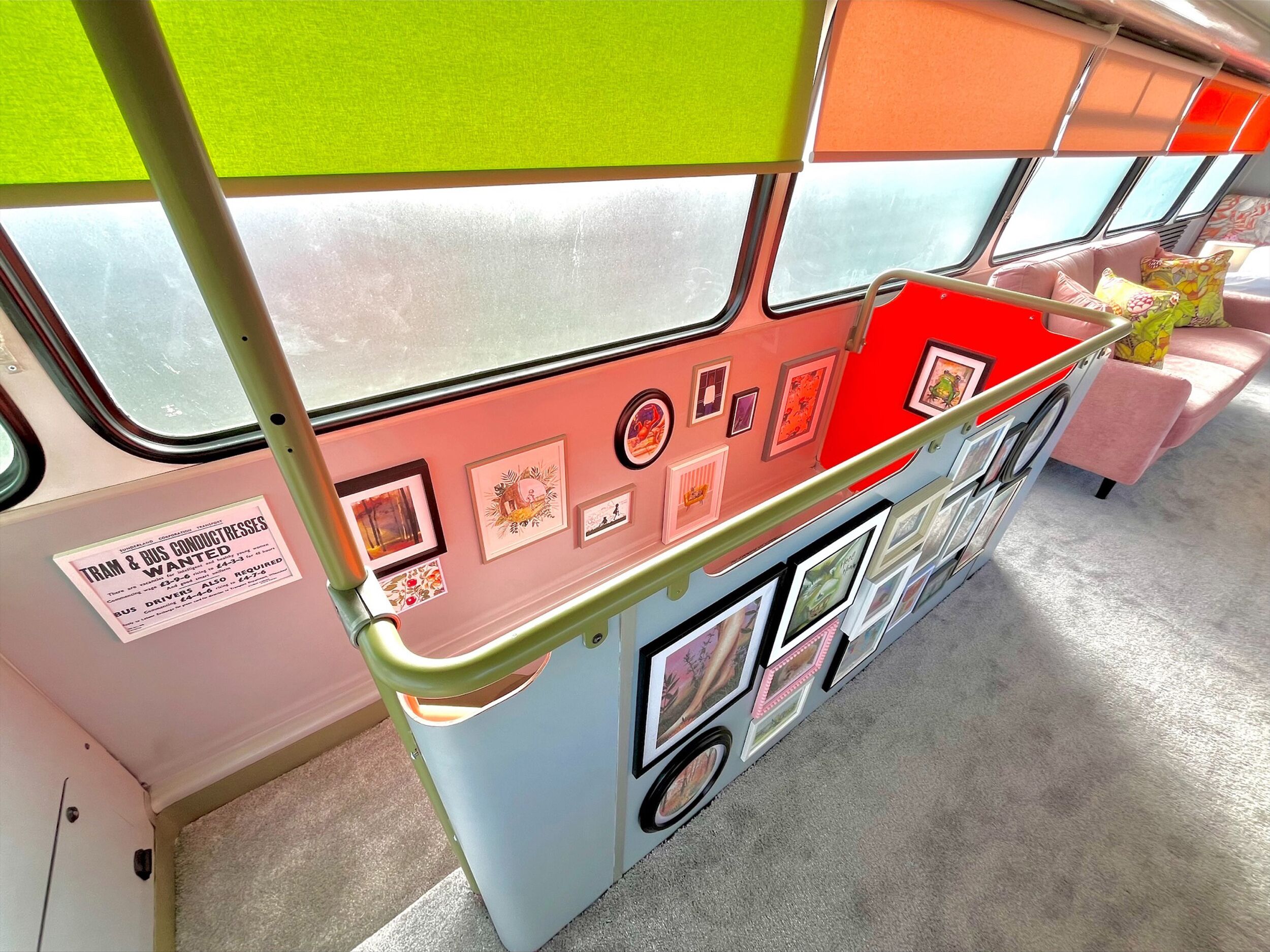 Interior de ônibus com assento vermelho, painel de avisos e obras de arte nas paredes.