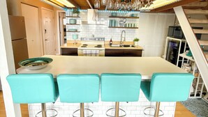 A kitchen with a central island, bar stools, and a staircase leading to an upper level. - The Little Penthouse is a charming two-level condo located in the gated Southwood Shores. This comfortable retreat offers access to resort style amenities including indoor and outdoor pools, a hot tub, playground, swimming area. (Lake Ozark)