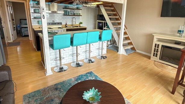 A loft-style living space with a dining area, kitchen, and a staircase leading to an upper level. - The Little Penthouse is a charming two-level condo located in the gated Southwood Shores. This comfortable retreat offers access to resort style amenities including indoor and outdoor pools, a hot tub, playground, swimming area. (Lake Ozark)