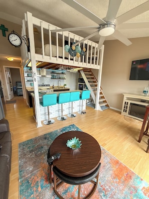 Un espace de vie de style loft comprenant un coin repas, une cuisine et un escalier menant à un niveau supérieur.