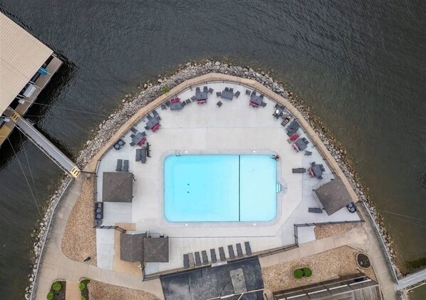 Vue aérienne d’une piscine avec des chaises longues et un espace de détente.