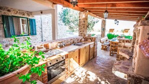 Une cuisine extérieure rustique avec des murs en pierre, des poutres en bois et un four encastré.