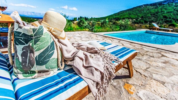 Un salon de bord de piscine avec vue sur une montagne, un chapeau et une couverture.