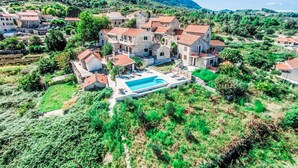 Un village côtier aux bâtiments en pierre, doté d’une piscine et entouré d’une végétation luxuriante.