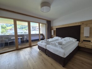 A bedroom with a large bed, a wooden headboard, a sliding glass door leading to an outdoor area, and a ceiling light fixture. - 3_SPA - Poolside Superior 726 by Interhome (Zell am See)