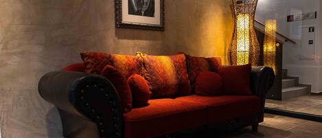 A modern interior with a red sofa, a framed picture on the wall, and a staircase with a decorative light fixture.