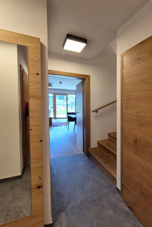 A hallway with wooden doors, a staircase, and a ceiling light. - 3_SPA - Poolside Superior 726 by Interhome (Zell am See)