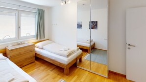 Un dormitorio con cama, cómoda, espejo y ventana.