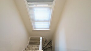 A staircase with striped carpet leading to a landing.