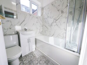 Ein Badezimmer mit Toilette, Waschbecken, Badewanne und Dusche.