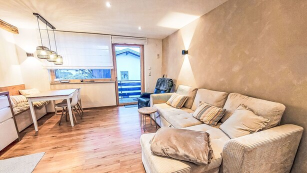En moderne stue med sofa, spisebord og et køkkenområde.