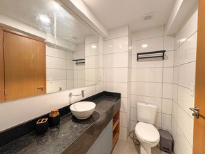 A modern bathroom with a large mirror, a sink, a toilet, and a shower area. - Max Carneiros Suites - Praia dos Carneiros by CTA (Tamandaré)