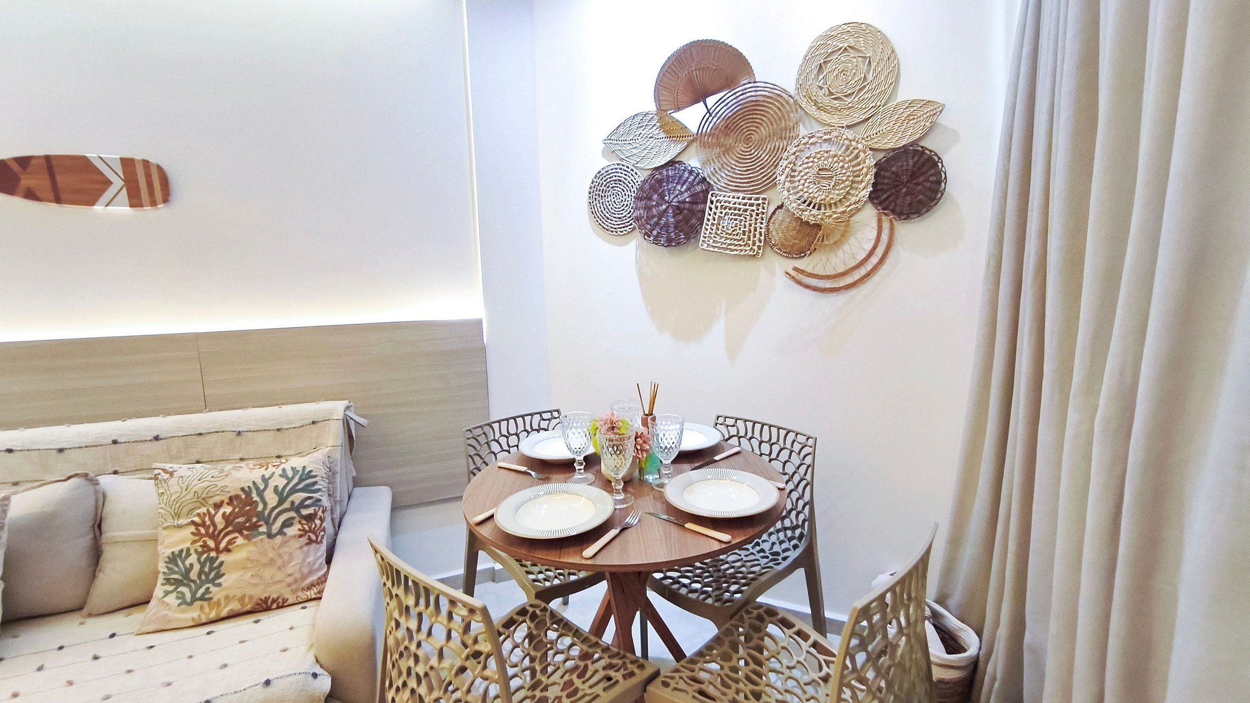 Un comedor con una mesa redonda, sillas y un elemento decorativo en la pared.