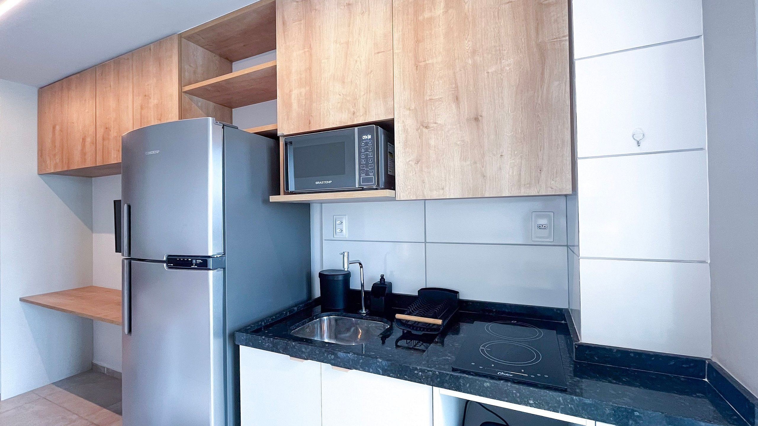A compact kitchen with a refrigerator, microwave, and induction cooktop.